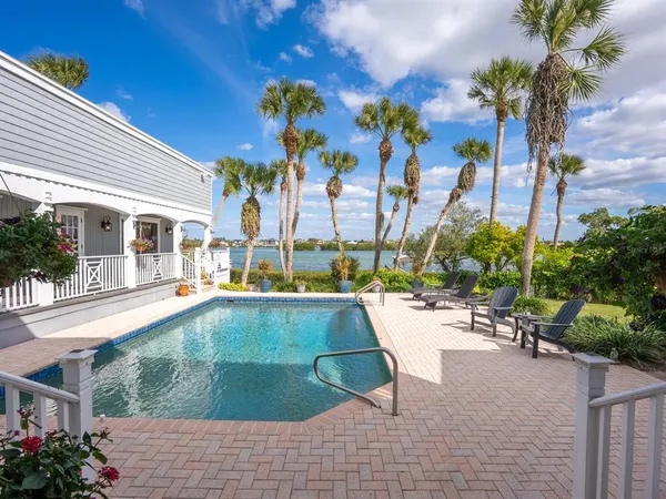 a view of a white house with a big yard and potted plants