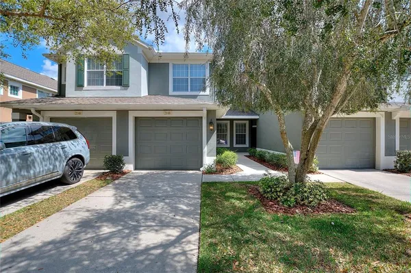 a view of a house with a yard and large tree