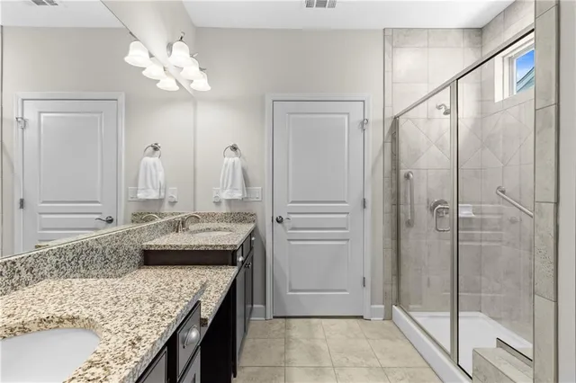 a bathroom with a granite countertop sink a mirror and shower