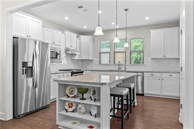 a kitchen with stainless steel appliances granite countertop a refrigerator a sink dishwasher a stove and a refrigerator with wooden floor