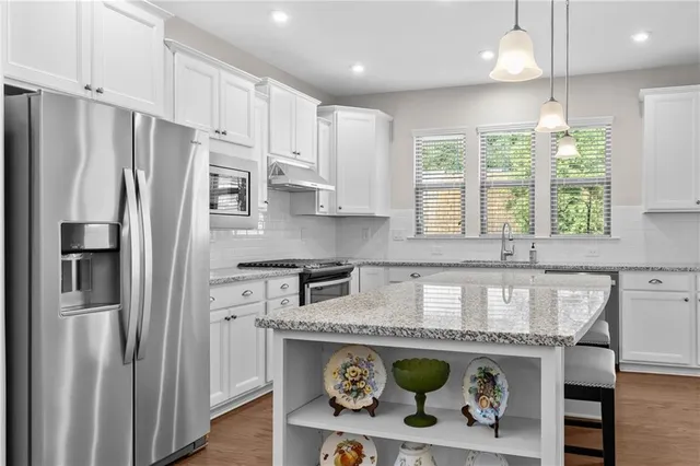 a kitchen with stainless steel appliances granite countertop a refrigerator a sink and a stove