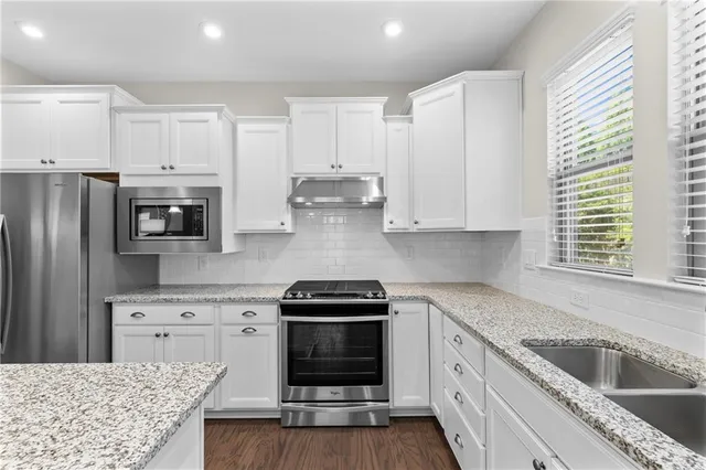 a kitchen with granite countertop white cabinets and stainless steel appliances