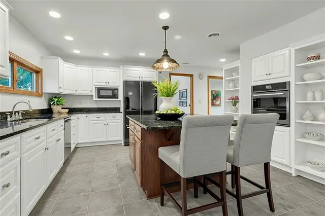 a kitchen with stainless steel appliances granite countertop a table chairs sink refrigerator and cabinets