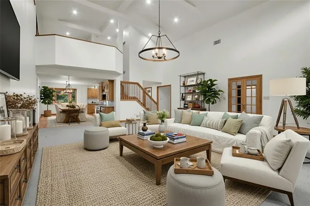 a living room with furniture kitchen view and a chandelier