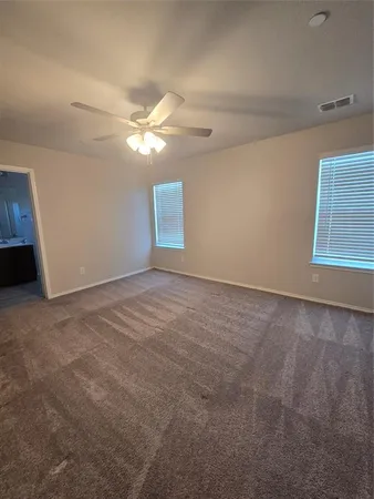 an empty room with windows and fan