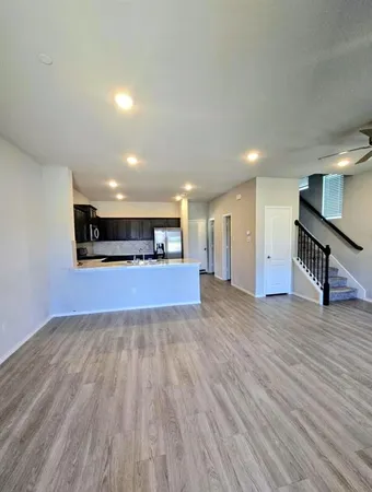 a view of an empty room with wooden floor and a hallway