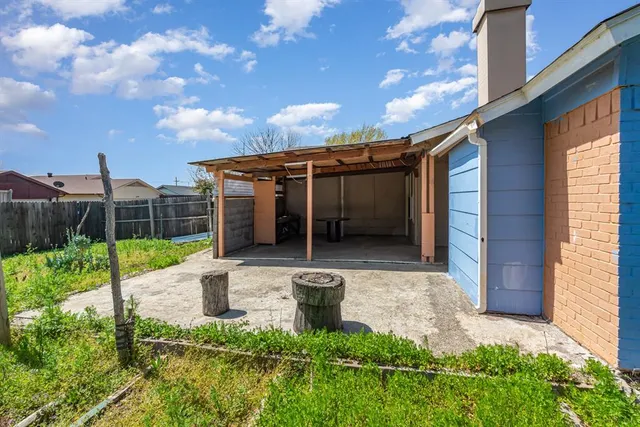 a view of a patio with table and chairs with plants and wooden fence
