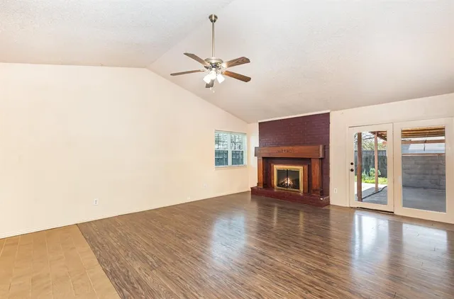 a view of an empty room with window and wooden floor