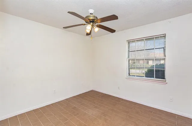 an empty room with window and ceiling fan