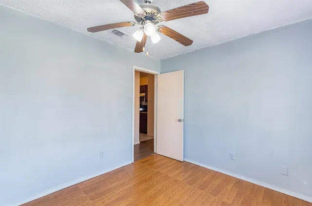 an empty room with a chandelier fan and a ceiling fan