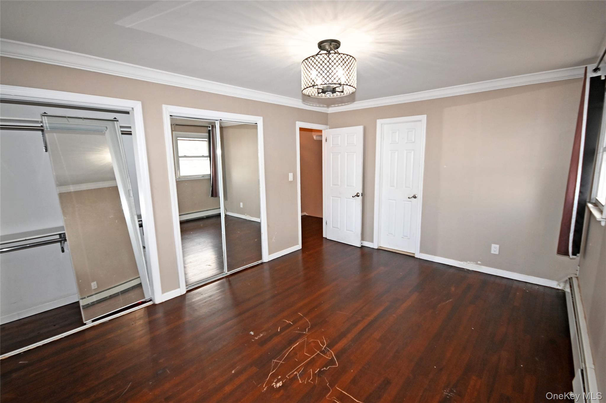 89 Osborne Road West Hempstead, NY 11552 - Photo 14 of 50 Unfurnished bedroom with two closets, ornamental molding, dark wood-style floors, and baseboard heating