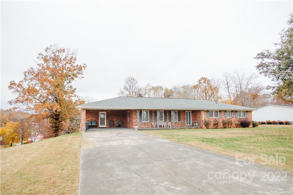 a view of a white house with a large tree and plants