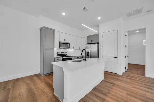 a view of a kitchen with stainless steel appliances a refrigerator and a stove top oven