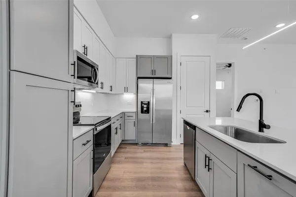 a kitchen with stainless steel appliances granite countertop a sink and a refrigerator