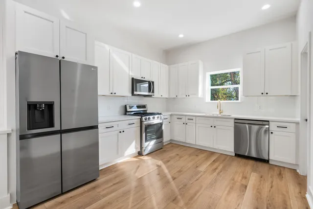 a kitchen with white cabinets stainless steel appliances and window