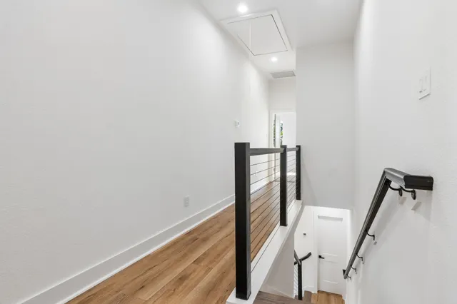 a view of a hallway with wooden floor and stairs