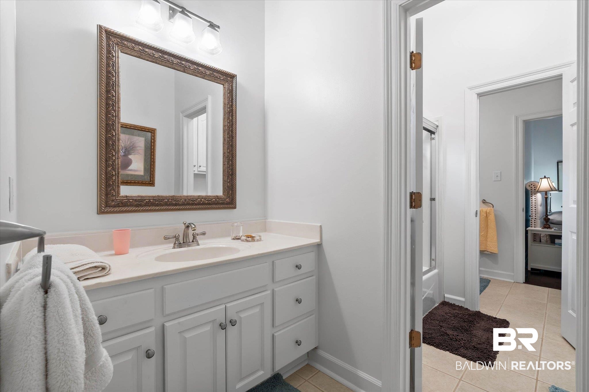 136 Old Mill Road Fairhope, AL 36532 - Photo 22 of 36 Bathroom vanity featuring white cabinetry, a light-toned countertop, and a single sink with a brushed nickel faucet