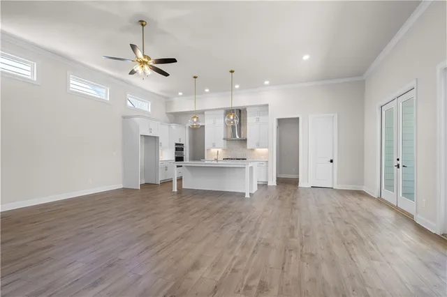 a view of an empty room and kitchen with sink wooden floor and a window