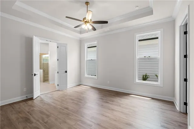 an empty room with wooden floor chandelier fan and windows