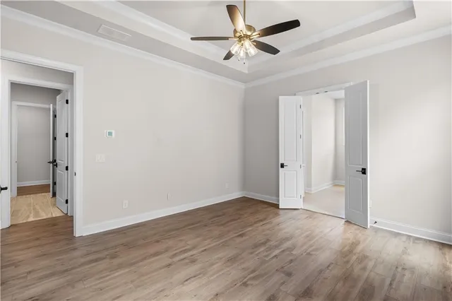an empty room with wooden floor and a ceiling fan