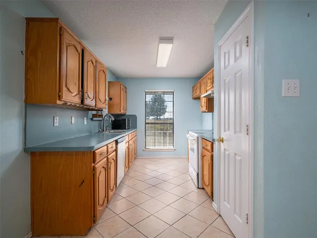 a kitchen with stainless steel appliances granite countertop a refrigerator a stove a sink and dishwasher with wooden cabinets