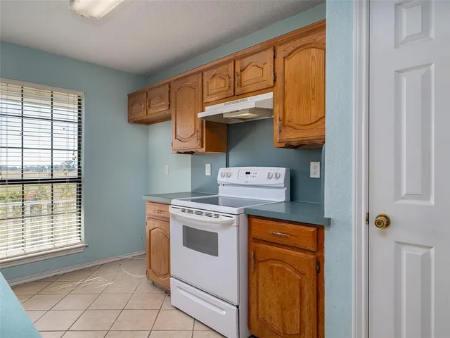 a kitchen with a stove top oven cabinets and a window