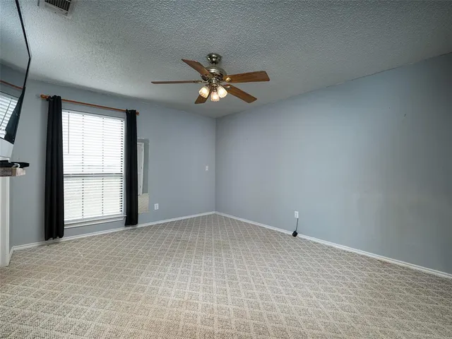 an empty room with chandelier fan and windows
