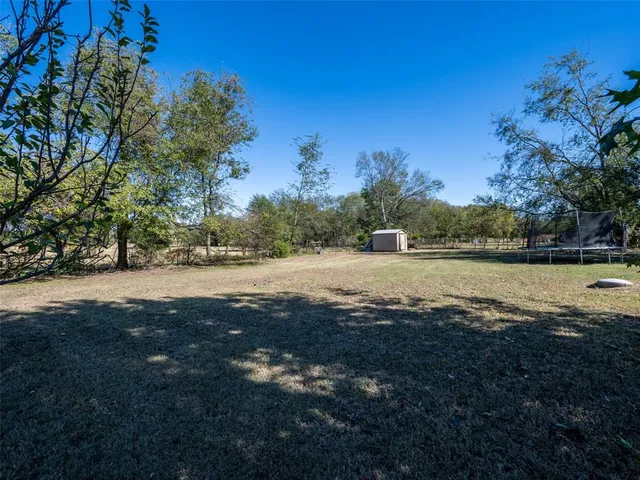 a view of dirt field with large trees