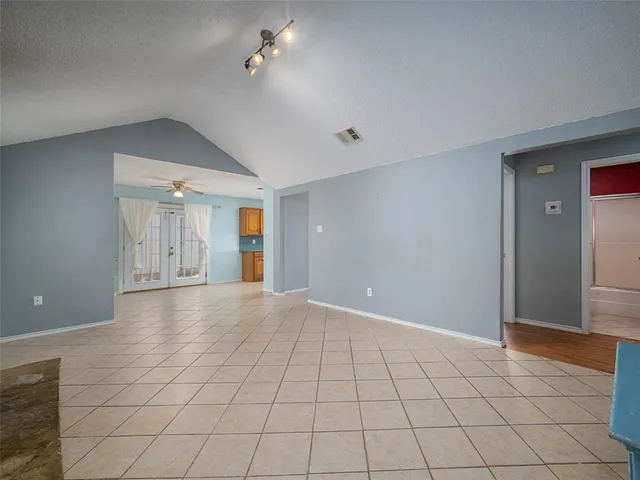 a view of an empty room with window and chandelier fan