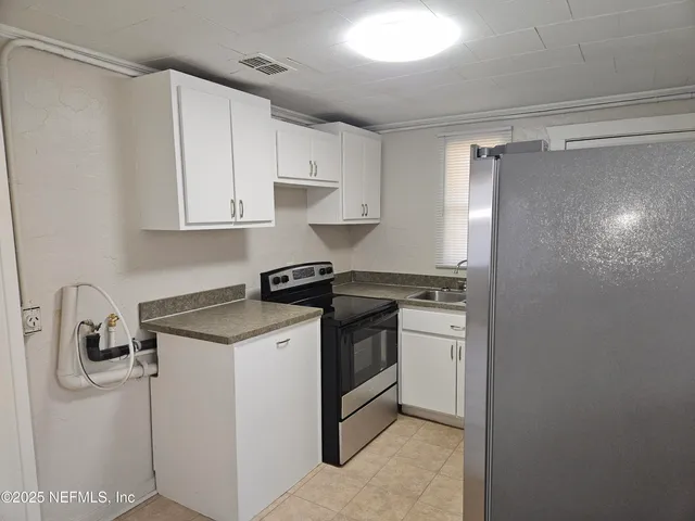 a kitchen with stainless steel appliances granite countertop a sink and a refrigerator