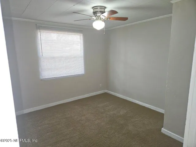 an empty room with a window and ceiling fan