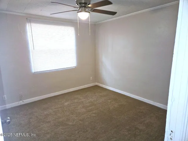 an empty room with a window and a fan