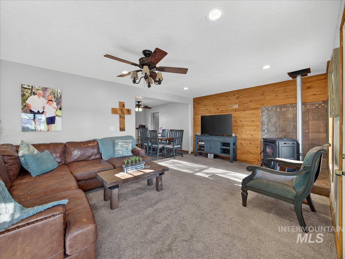 2588 West Sales Yard Road Emmett, ID 83617 - Photo 28 of 49 Living area with a wood stove, wooden walls, carpet flooring, recessed lighting, and ceiling fan