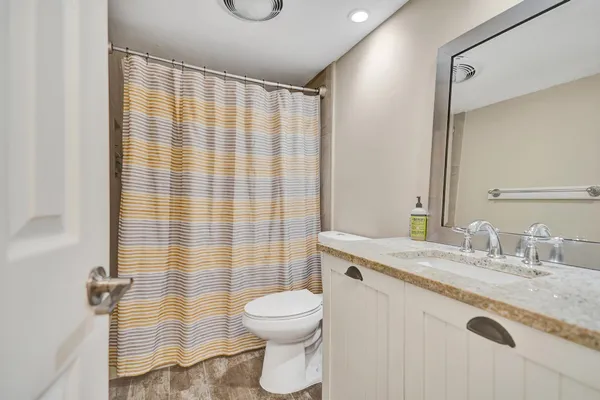 a bathroom with a granite countertop sink a toilet and shower curtain