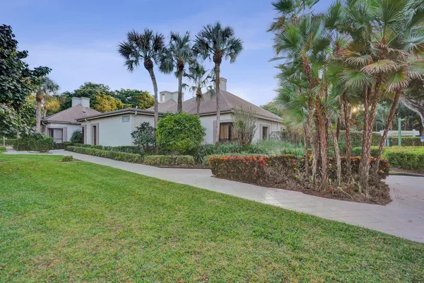 a front view of a house with a garden and tree