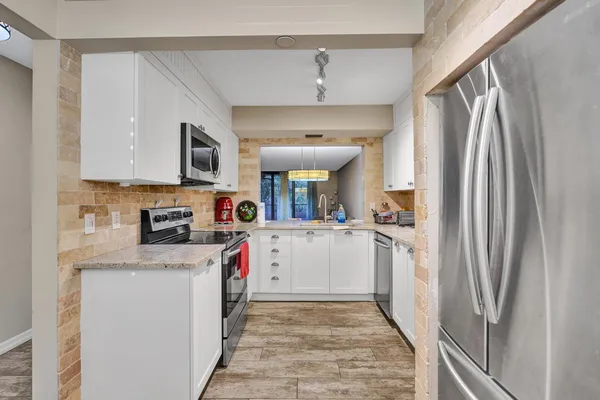 a kitchen with stainless steel appliances granite countertop a refrigerator and a stove top oven