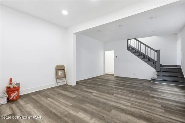 a view of a livingroom with wooden floor and stairs