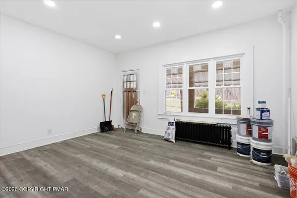 a view of an empty room with a window and wooden floor