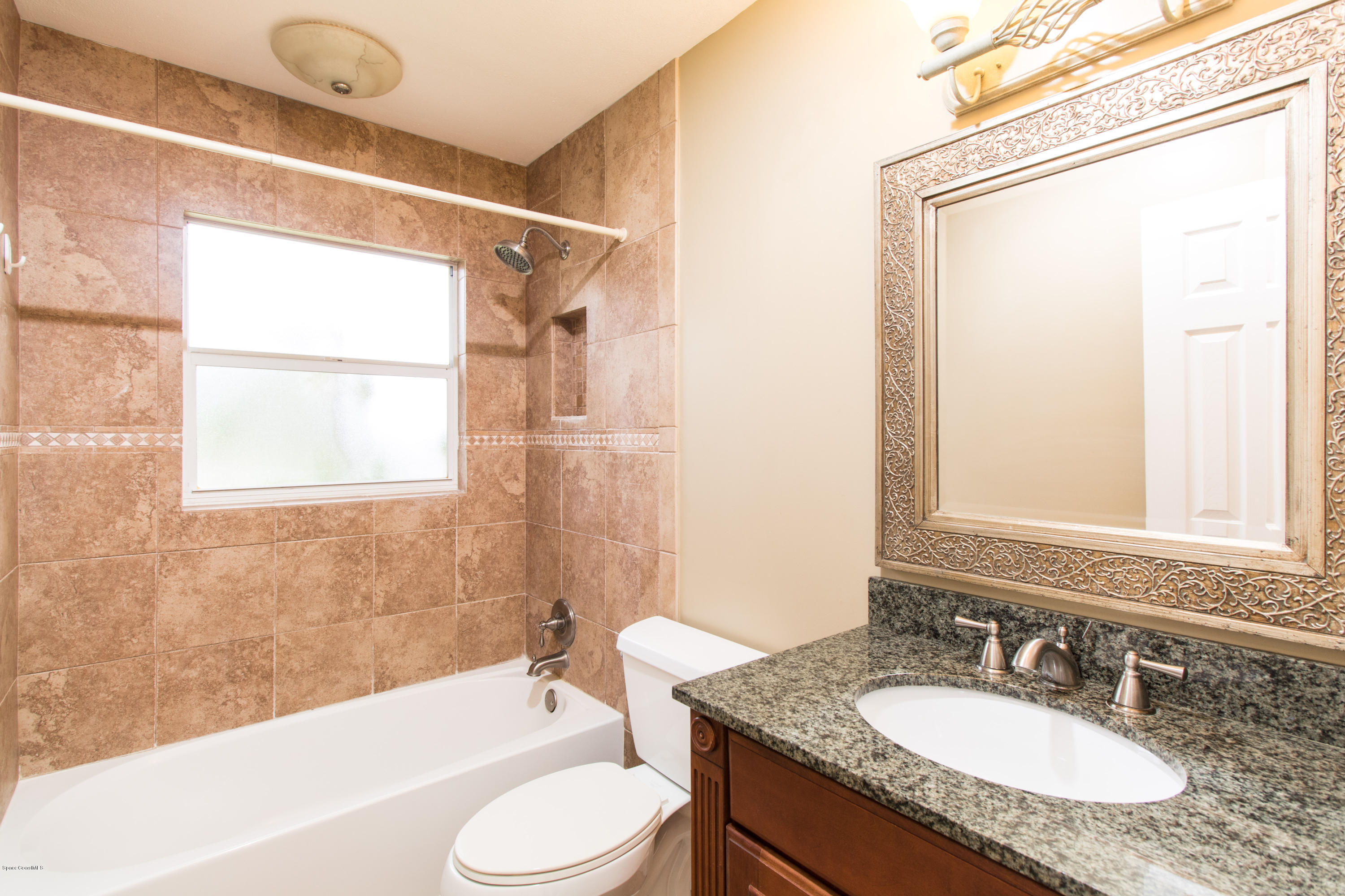 1054 Bali Road Cocoa Beach, FL 32931 - Photo 13 of 24 a bathroom with a granite countertop sink toilet and shower