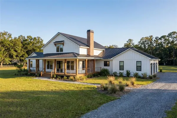 a view of a house with a big yard and large trees