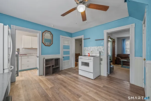 a view of a livingroom with a fireplace a ceiling fan and wooden floor