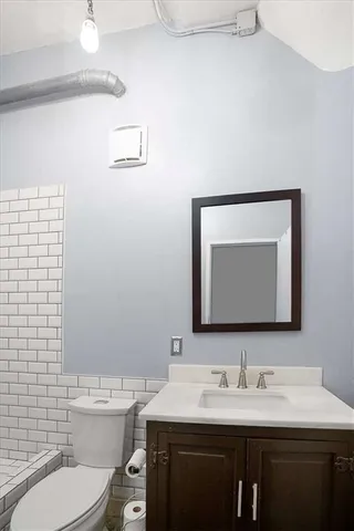 a bathroom with a toilet sink vanity and mirror