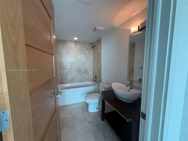 a bathroom with a tub sink toilet and a mirror