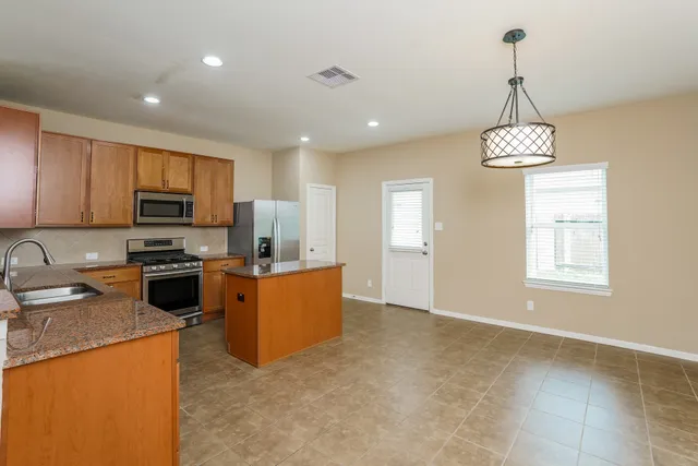 a kitchen with stainless steel appliances granite countertop a stove top oven a refrigerator a sink dishwasher with a dining table and chairs