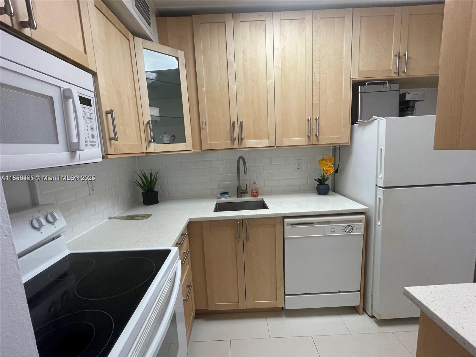 2899 Collins Avenue, Unit 1420 Miami Beach, FL 33140 - Photo 6 of 17 a kitchen with a sink and a refrigerator