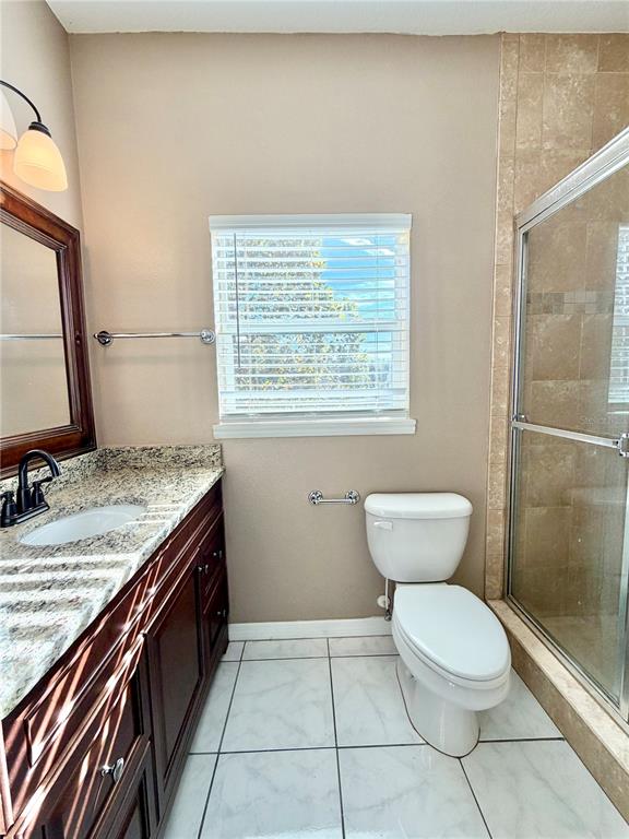 4848 Tampa Downs Boulevard Lutz, FL 33559 - Photo 11 of 27 a bathroom with a granite countertop toilet a sink and a mirror