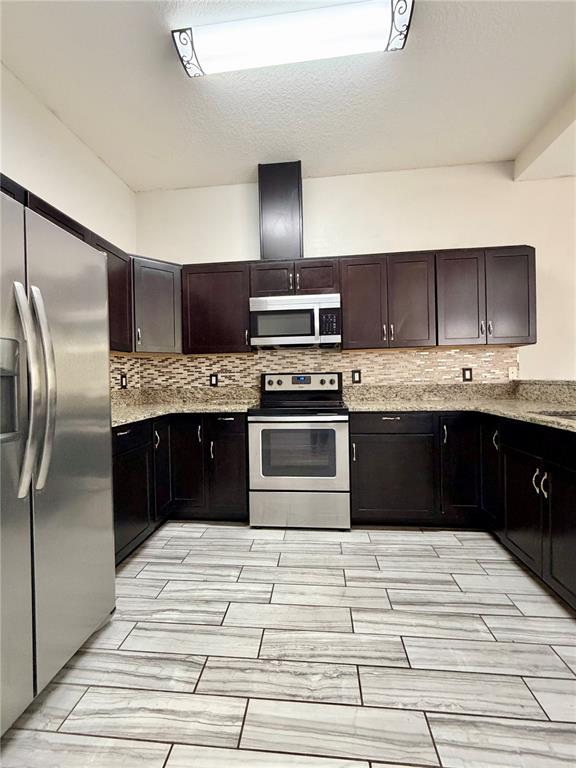 4848 Tampa Downs Boulevard Lutz, FL 33559 - Photo 3 of 27 a kitchen with stainless steel appliances granite countertop a stove a refrigerator and a sink