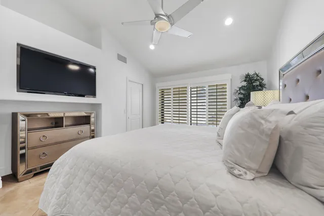 a large white bed sitting in a bedroom and flat screen tv