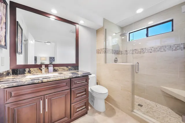 a bathroom with a granite countertop sink a toilet and a shower