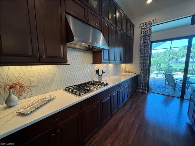 a kitchen with stainless steel appliances granite countertop a stove a sink dishwasher and cabinets with wooden floor